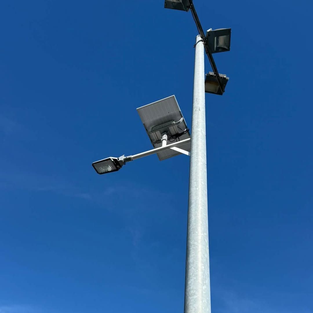 Mât galvanisé avec lampadaire solaire et projecteur sous ciel bleu
